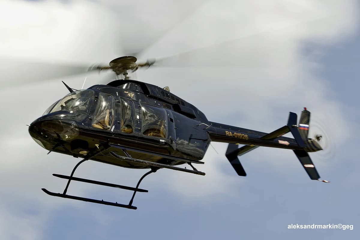 A Bell 407 in flight, photographed from below and to the side