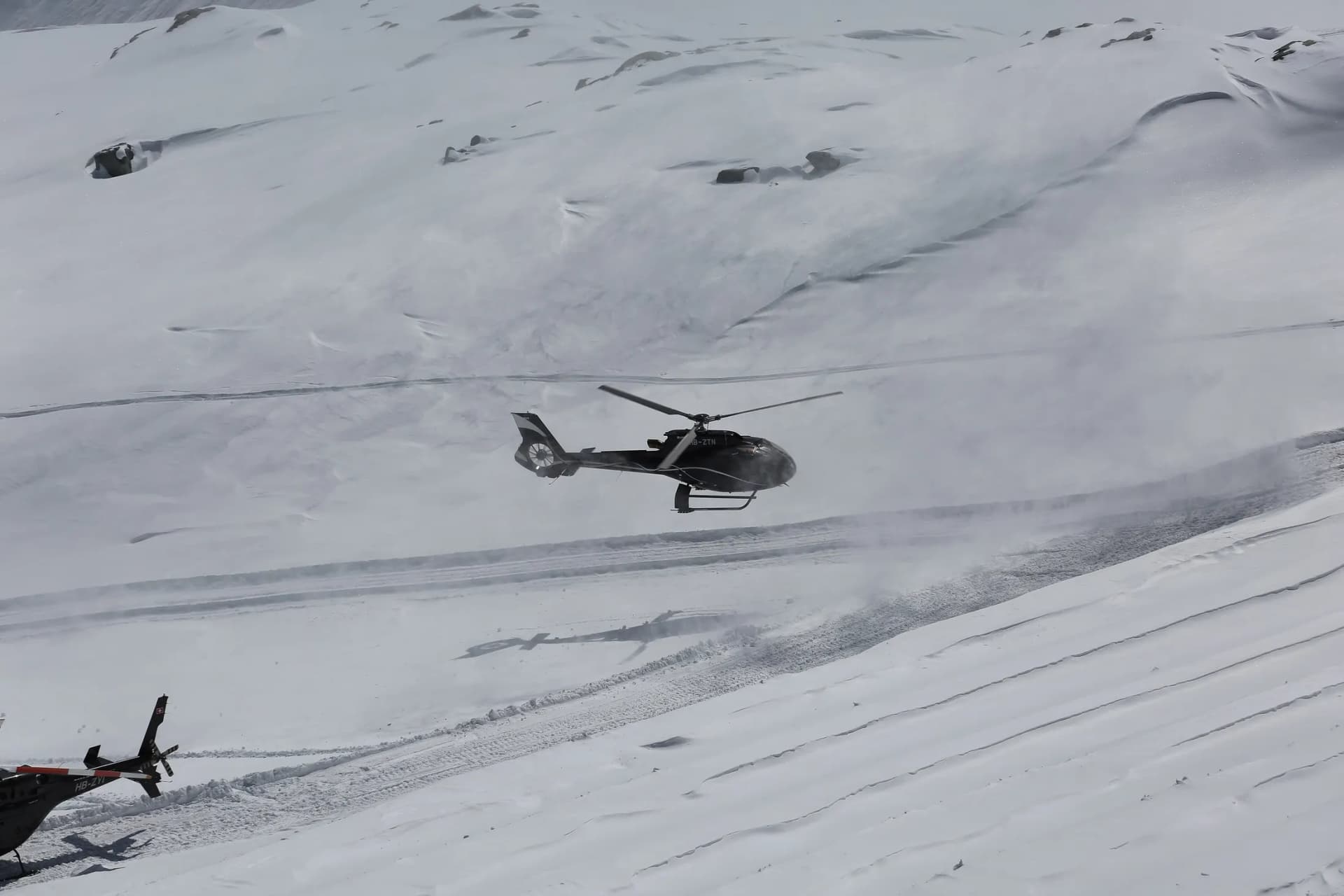 An Airbus H130 flying above the snowy Piz Corvatsch mountain ridge
