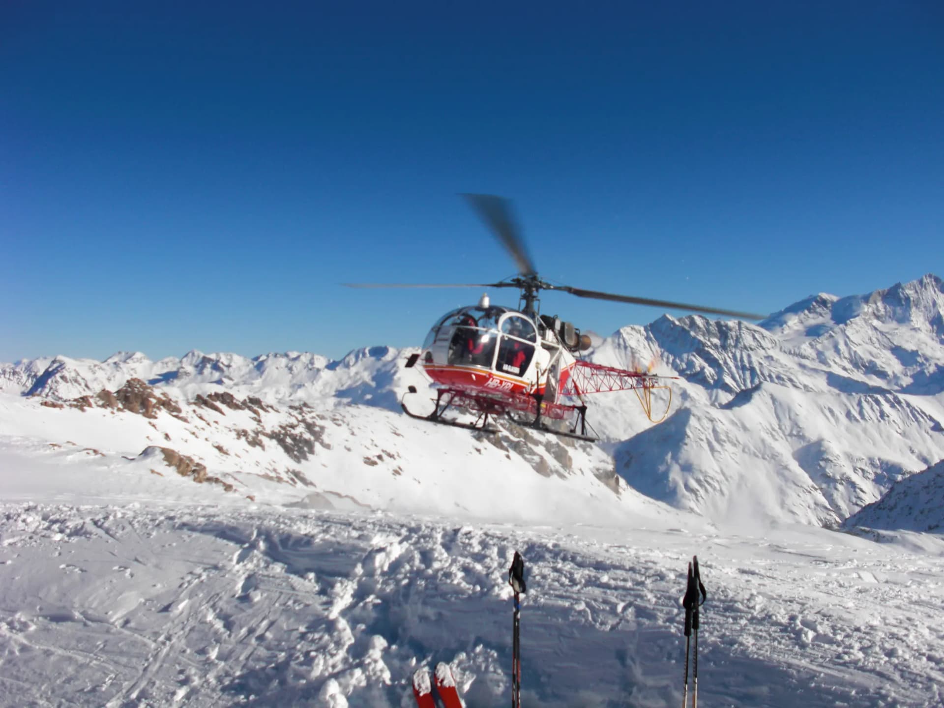 An SA315B Lama approaching above a snow-covered Alpine valley