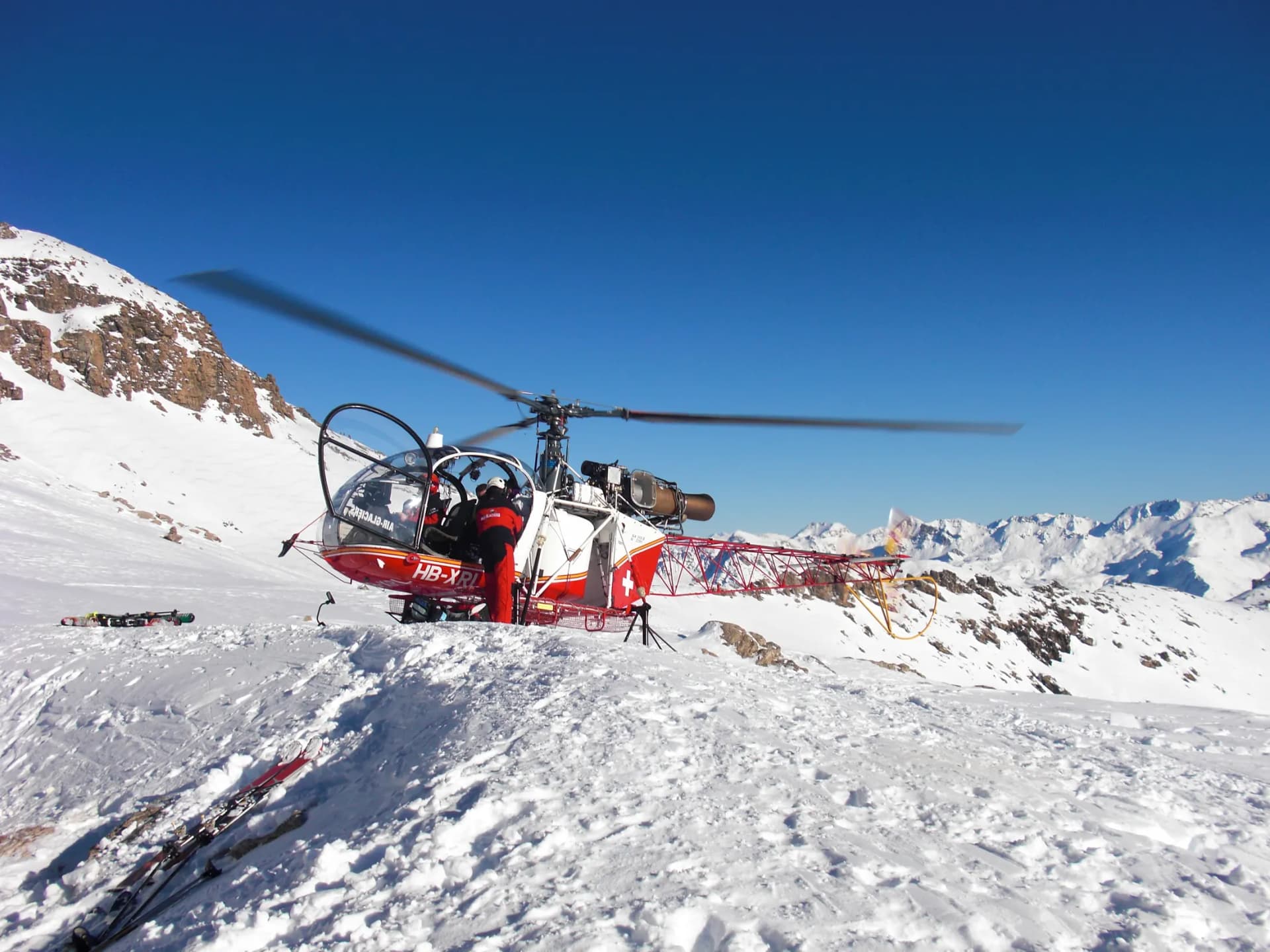 Passengers boarding an SA315B Lama through its open cabin door on snow